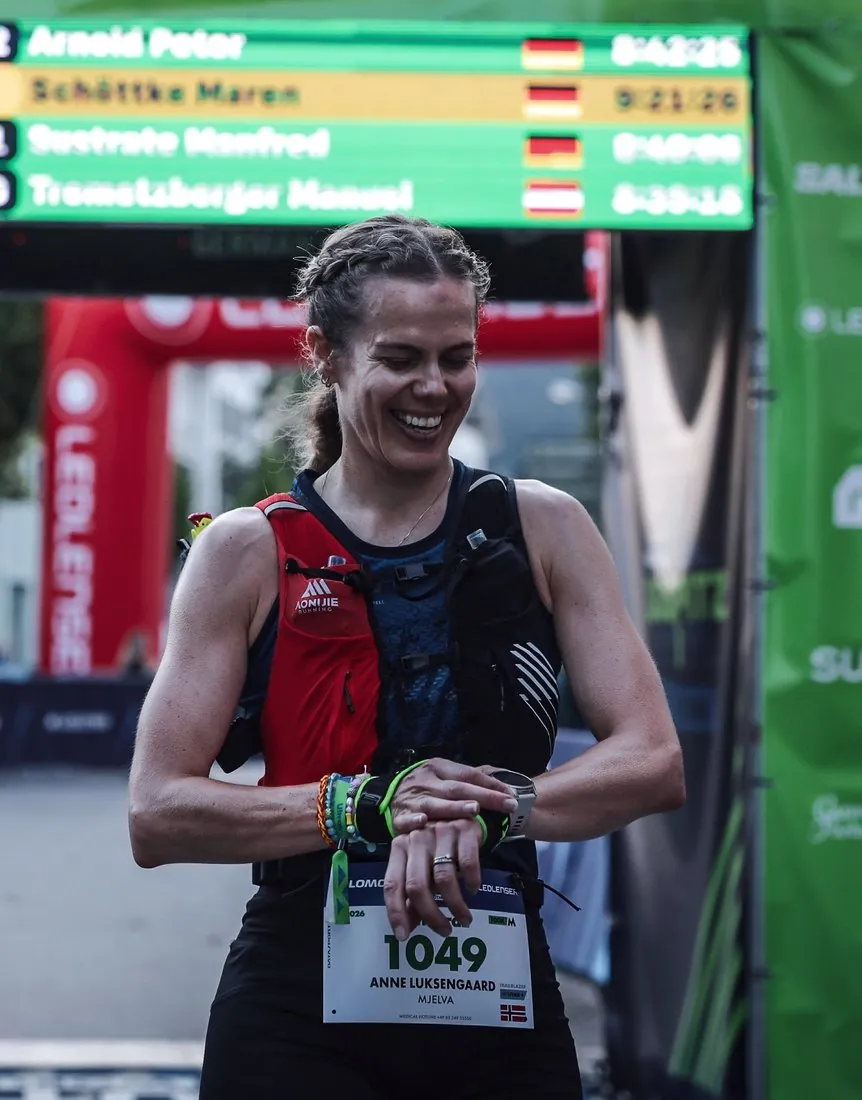 Anne Mjelva i målområdet etter Zugspitz Ultratrail, med startnummer og resultattavle bak seg.